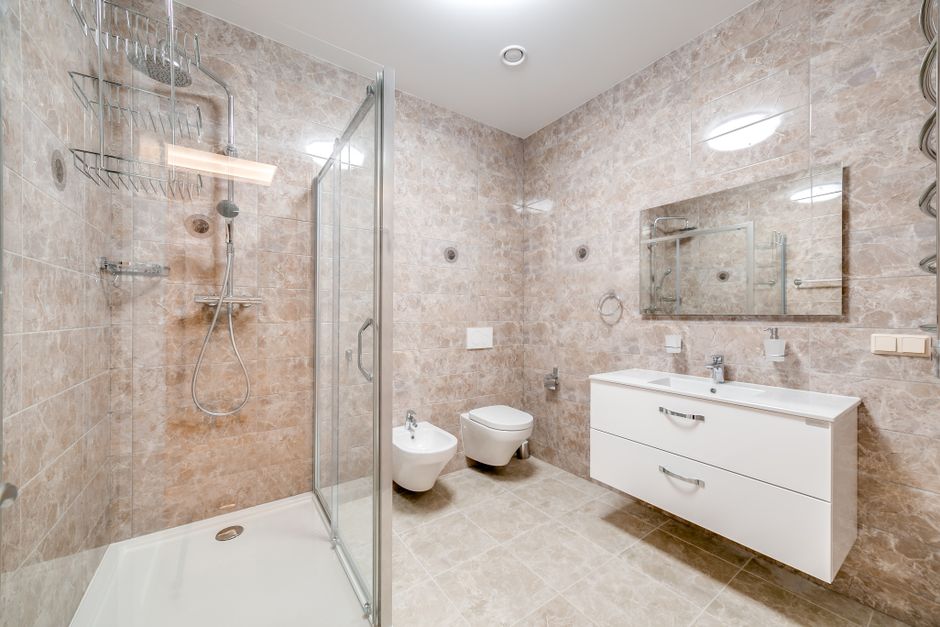 A residential bathroom featuring a built-in corner bathtub with a smooth, glossy white surface, accessorized with a neatly folded white towel draped over the edge. The bathtub is fitted with modern ch